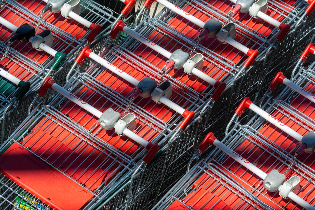 Neatly arranged shopping carts casting shadows under bright sunlight, showcasing a supermarket exterior.